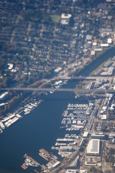 Aerial view of Aurora Bridge to Fremont, north of Seattle - with the blue water below lined with marinas filled with boats. Again, with a tilt-shift effect from the aircraft's jet engine, making the scene look so very small...