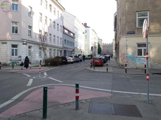 Kreuzung mit Poller und Bemalungen als Diagonalsperre für KFZ, Person mit Kind quert zu Fuß