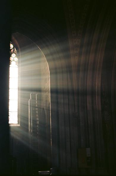 Licht, welches durch die neugotischen Fenster der Votivkirche in Wien ins Kirchenschiff eindringt.