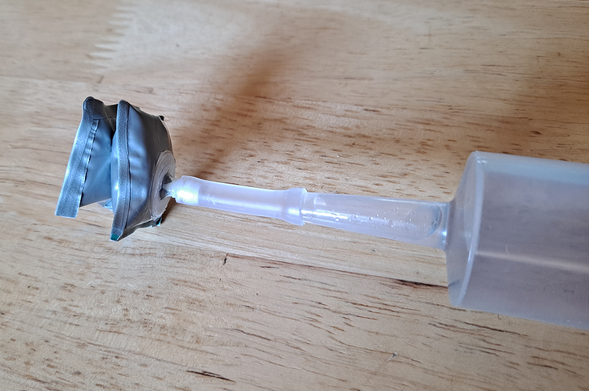 A little "bladder" that looks like two stacked pillows made of silver sheet plastic, with an inlet valve on the bottom side of one pillow, connected to a big syringe via a little piece of tubing.
