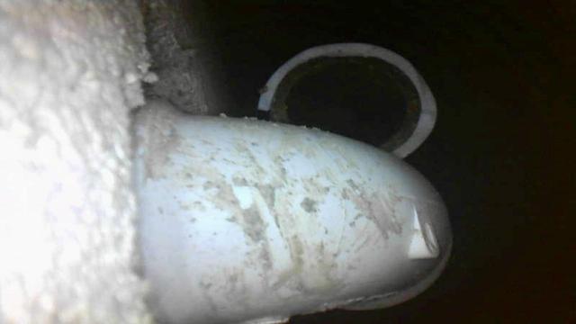 An endoscopic top-down view of a pipe disconnected from its elbow behind the drywall.