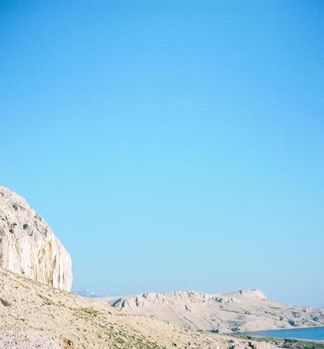 Blue sky with mountains and rocks below.