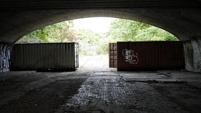 view under a bridge towards some shipping containers, poorly tagged