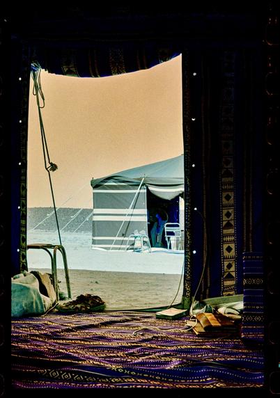 Looking out through the door of a tent at another Bedouin style tent a few meters away.