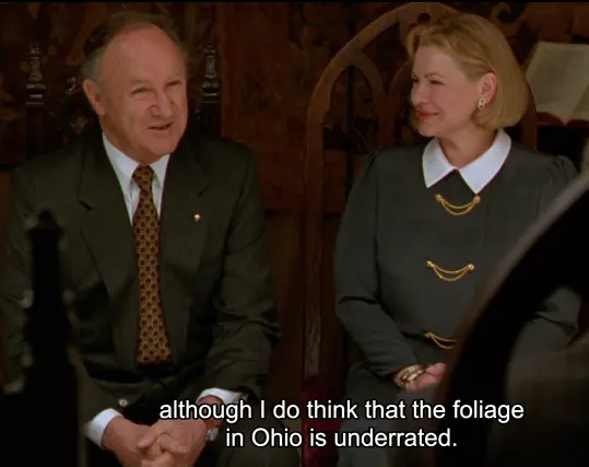 Senator Keeley (Gene Hackman) says "although I do think that the foliage in Ohio is underrated." his wife Louise Keeley (Dianne Wiest) smiles next to him. they're wearing formal outfits in black and white