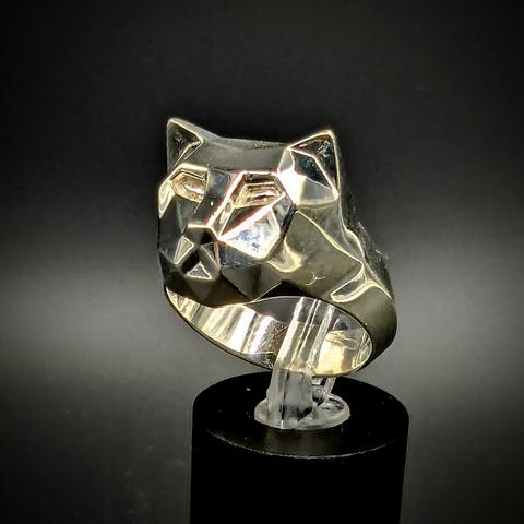 Vue de 3/4 sur la bague en argent polie. La tête de chat est polygonnalisée. Façon 3D low res. Fond noir