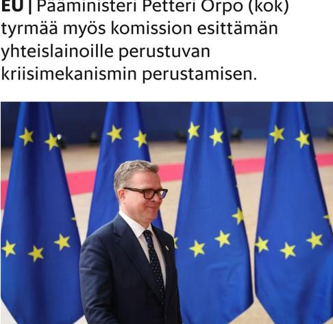 Petteri Orpo sinisessä puvussa takanaan EU:n lippurivistö, astelemassa hymyillen puhumaan.
