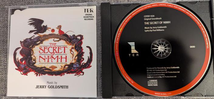 Photo of the cover and CD.

The cover shows Mes Brisby, a small, brown mouse with a red cape, and Jeremy the crow, on top of a big wooden frame made out of tree roots that encircle the text logo "The Secret of NIMH"

Sitting and climbing this frame of root are other characters from the movie: Mr Ages, Dragon the cat, Aunty Shrew and  Martin Brisby.

On top of the frame there's text: "A Don Bluth Production"

On top of the cover text reads: "TER Original soundtrack recording" and at the bottom "Music by: Terry Goldsmith"

The CD itself has a black cover with a red outer frame and lists, in addition to production company and copyright notes, "Music by Jerry Goldsmith, Lyrics by Paul Williams"