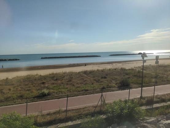 Photo shot through the window of the night train after waking up: the Mediterranean and a beach just beside the train.