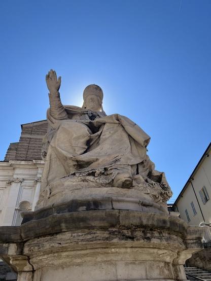 Statue of the pope in the old town. Sun is hiding behind the pope's head.