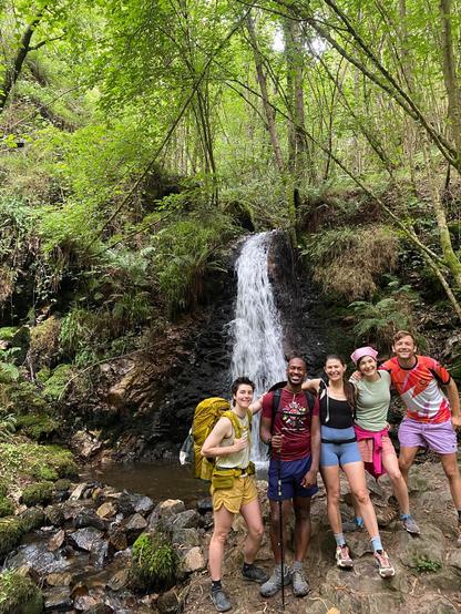 A group of five standing in front of a small waterfall