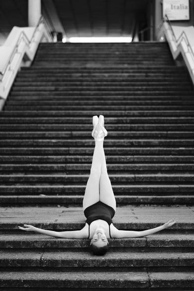 Balletttänzerin kopfüber auf einer Treppe liegend, die Beine in die Luft gestreckt