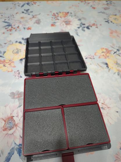 A Gridfinity box, whose outer shell is printed from a dark grey plastic. The inside boxes are a dark red plastic, with dark grey flip lids to match the outer shell. Two boxes are 2 by 2, and one is 4 by 2. All the flip lids are closed. The latch is visible, and it is the same dark red as in the inside boxes.