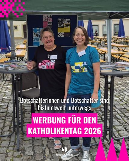 Zwei Frauen stehen an einem Messestand. Im Hintergrund sind Flyer des Katholikentags zu sehen.
