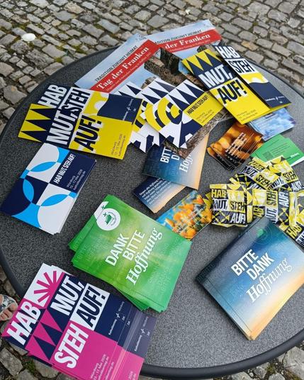 Flyer mit der Aufschrift "Hab Mut, steh auf" liegen auf einem Tisch.