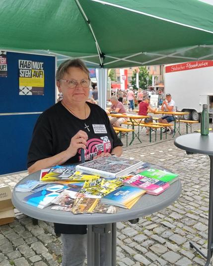 Eine Frau steht an einem Stehtisch eines Messestandes.