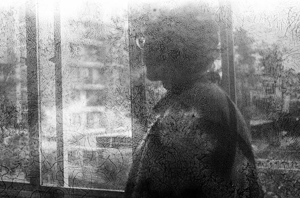 Fotografia em preto e branco mostra a silhueta de uma pessoa de perfil olhando pela janela enquanto fuma.A imagem está coberta por texturas orgânicas, veios de fungos, pois foi usado um filme vencido para capturar a imagem, o que criam um efeito de desgaste e sobreposição.