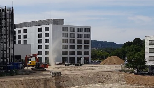 Eine Baustelle mit größerer Freifläche auf der sich eine Staubsäule gebildet hat.