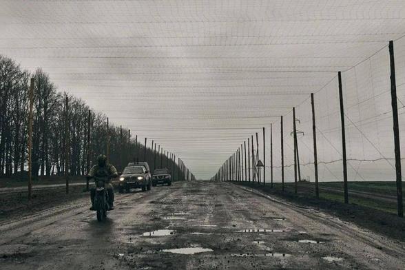 A road to the Russian border is covered with netting to protect against FPV kamikaze drones in Sumy Oblast, Ukraine, Spring 2025