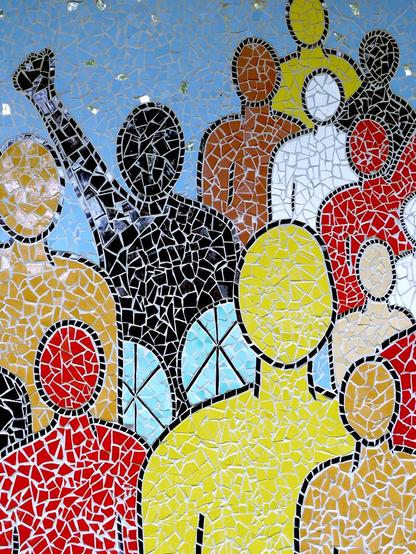 Tile mosaic of human-shaped figures of various colours. A figure composed of black tiles has their fist raised above their head.