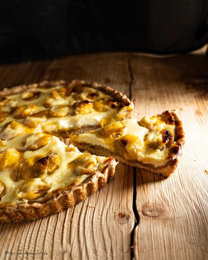 Heller Holzuntergrund. Darauf eine Mirabellentarte.