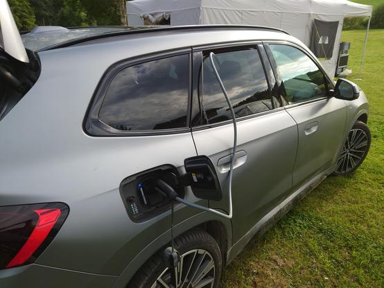 Elektroauto, das durch einen Typ 2 Stecker geladen wird, der aus dem Heckfenster kommt.