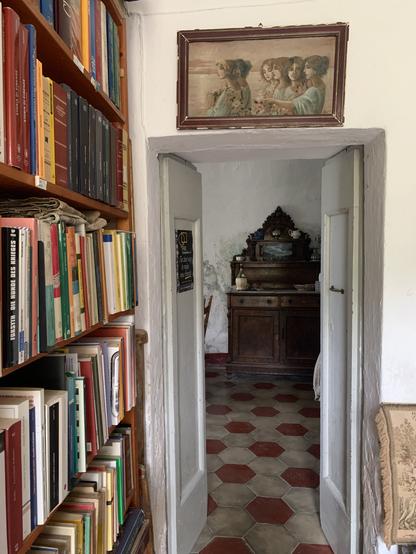 Parte di casa , una libreria una porta in legno e una credenza antica con ripiano di marmo pavimento di cementine