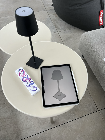 ipad on a coffee table with a small black LED lamp which is also sketched on the screen of the ipad