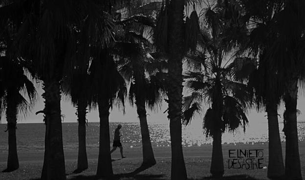 una persona caminando por la playa en b/n