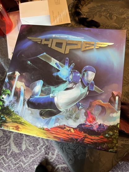 Photo of a board game box. It shows an astronaut flying in space with a planet behind them. The word “HOPE” is in big letters (the name of the game)