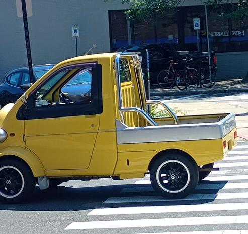 Small four wheel yellow truck. A single person cab, and a small bed.