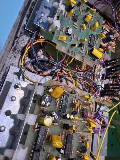 Looking across two separate small circuit boards, both with a lot of yellow colored components and black chips, surrounded by wires.