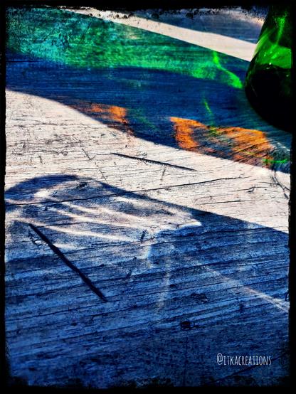 Sur une table en bois les reflets et les ombres (bleu, vert et marron) de verres et de bouteilles