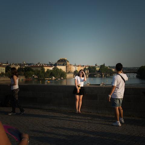 Portrait of a couple tourist, the man shooting the woman in front of a building in Prague
