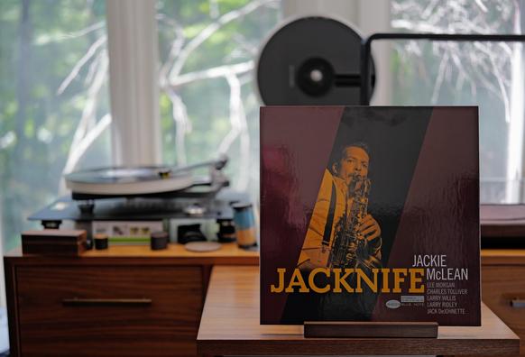 Jackie McLean - Jacknife LP cover.

A red/orange tinted picture of Jackie playing his sax, with the title at the bottom, credits bottom right.

The black LP plays on a Rega NAIA turntable to the left.