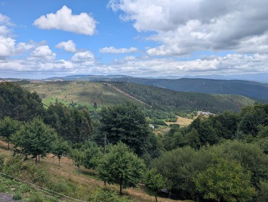 Vista point after a step ascent into A Fonsagrada. Trees in the foreground with mountains in the background