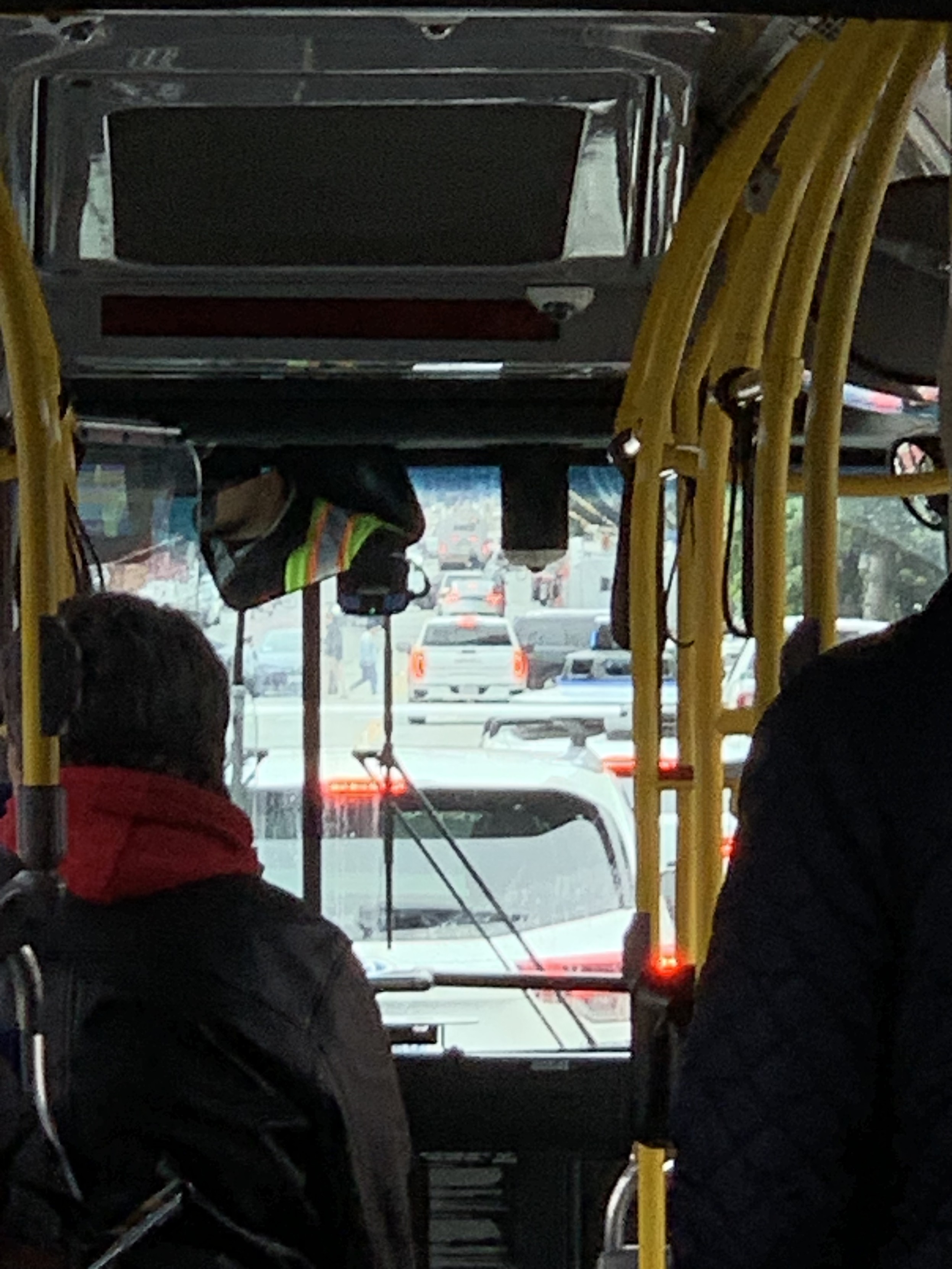 Zoomed photo out the front of a bus. There is a white SUV and in front of it a stopped Waymo.