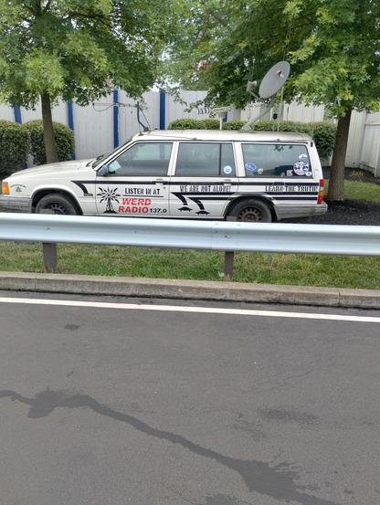 Volvo wagon unknown age, with too many antennas on it, most wouldn't do any good on a car, and I'm not really sure why you'd place them all close together like they are - on the side of the car is Conspiracy and Chill (with an eye in a pyramid). "Listen in At WERD Radio 137.0" next to a broadcast tower with lighting & ufos coming out of it. 
"We are not alone" with UFO picture, And "Learn the truth"
& various stickers on the back window