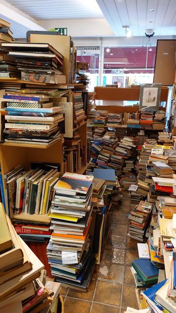 Tweedehands boeken in hoge stapels, de meeste op de vloer.