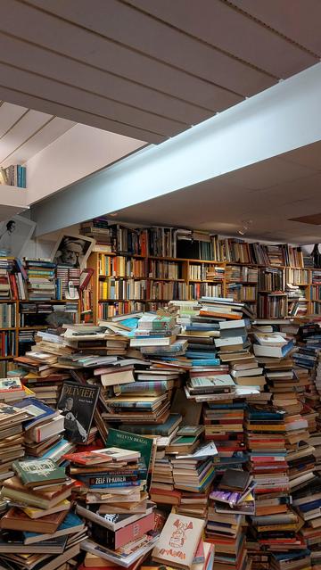 Tweedehands boeken in hoge stapels, de meeste op de vloer.