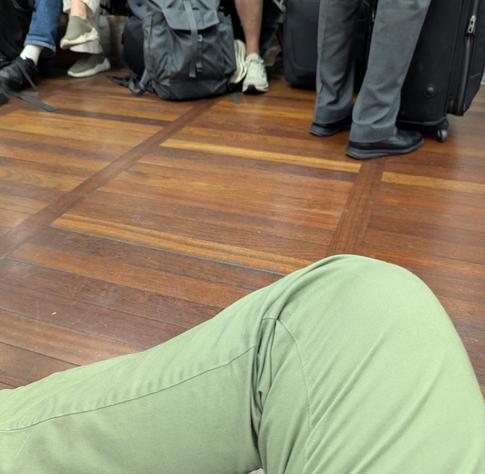 Me sitting on the floor. Many Shoes of other passengers next to me.