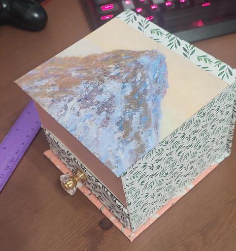 View from the top-bottomright corner  of a handmade hinged lid box with a drawer. Different decorations, with different patterns.