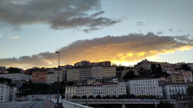 La colline de la Croix Rousse à Lyon au soleil couchant avec au dessus un nuage éclairé par en dessous allant de l'oranger à l'antracite