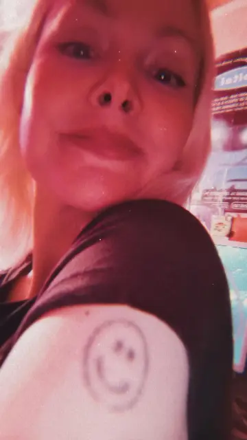 Me in my studio showing off a faded smiley face tattoo.