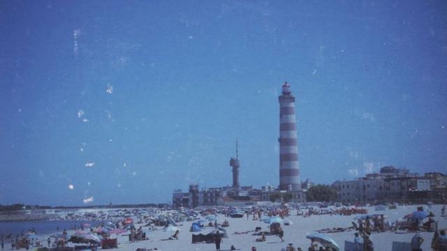 A busy beach and the lighthouse at Barra, Portugal.