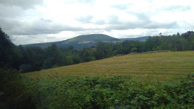 Far from great snap through a train window. Green fields and in the distance the Sugar Loaf mountain.