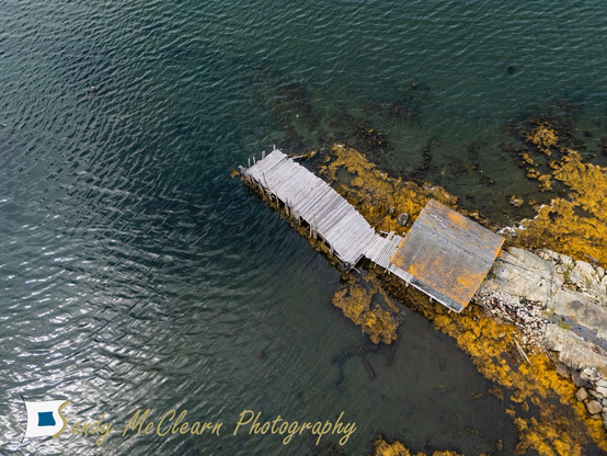 Aerial view of a wharf and shed sticking out into the water.