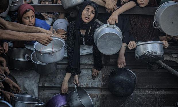 Un grupo de palestinos, agotados, hacen cola para recibir comida caliente distribuidas por la organización benéfica en la Ciudad de Gaza, el 16 de julio de 2025. (Ahmed Jihad Ibrahim Al-arini / Anadolu via Getty Images)