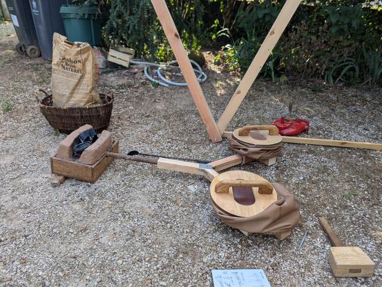 Sur le sol a l'extérieur, le foyer de la forge et les soufflets circulaires.