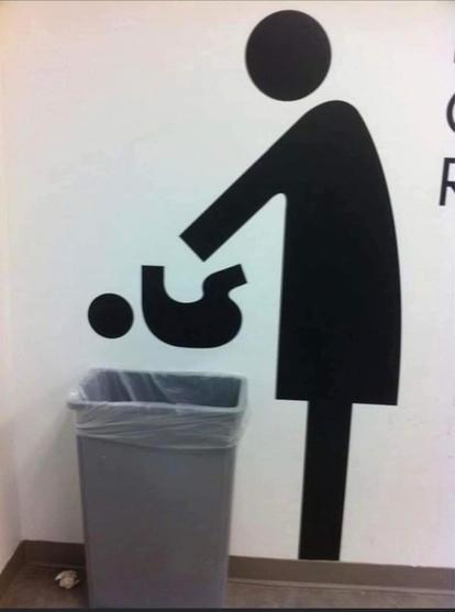 Photo of a bathroom wall. On it, there is a black representative image of a woman reaching down, and a baby is lying on its back in front of her. Under the baby is a garbage can where a changing table presumably was before. It seems like the baby is being thrown into the garbage can.